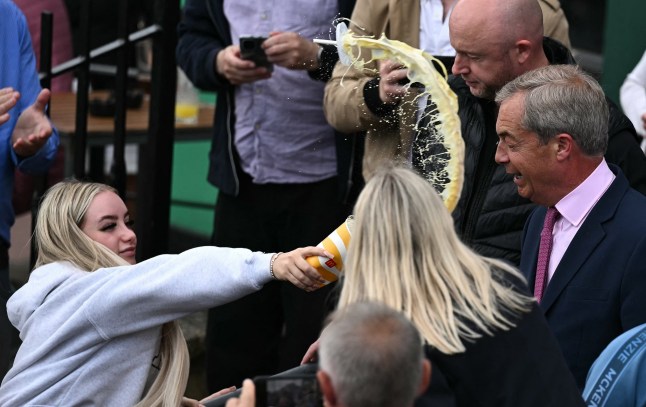 TOPSHOT - A person throws the contents of a drinks cup in the face of newly appointed leader of Britain's right-wing populist party, Reform UK, and the party's parliamentary candidate for Clacton, Nigel Farage, during his general election campaign launch in Clacton-on-Sea, eastern England, on June 4, 2024. Nigel Farage on Monday said he would stand as a candidate for the anti-immigration Reform UK party in Britain's general election next month, after initially ruling out running. "I have changed my mind... I am going to stand," Farage, 60, told a news conference. He will seek election on July 4 in the fiercely pro-Brexit seat of Clacton, southeast England. (Photo by Ben Stansall / AFP) (Photo by BEN STANSALL/AFP via Getty Images)