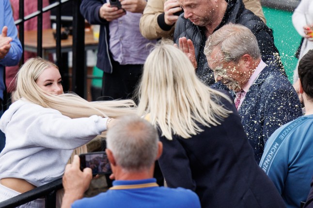 epa11389308 Nigel Farage (C), leader of Reform UK party and prospective parliamentary candidate for Clacton, reacts after a young woman threw a milkshake at him, during a campaign event in Clacton-on-sea, Essex, Britain, 04 June 2024. A 25-year-old woman has been arrested on suspicion of assault after a milkshake was thrown at Farage. Britain will hold a snap general election on 04 July 2024.?? EPA/TOLGA AKMEN