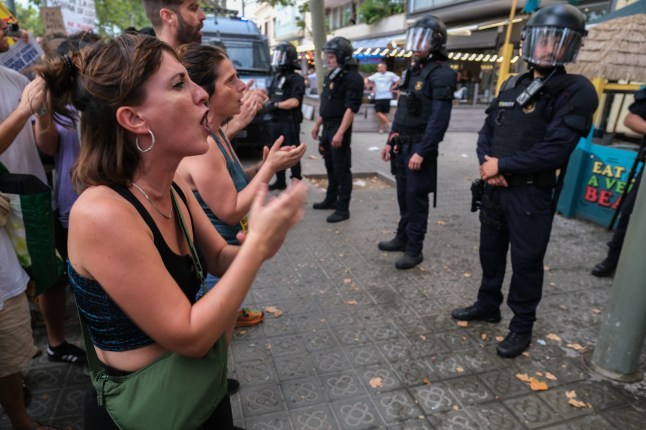 Mandatory Credit: Photo by Paco Freire/SOPA Images/Shutterstock (14575382z) Protesters are seen shouting slogans in front of a line of regional police officers protecting the terraces of Barceloneta restaurants mostly frequented by tourists during the rally. More than 3,000 people have demonstrated against the tourist overcrowding suffered by the city of Barcelona and in favor of tourism reduction policies. The demonstration has been symbolically closing hotel establishments, bars and restaurants while heading towards Barceloneta, one of the neighborhoods that suffers the most from the presence of tourism. Demonstration for tourism decrease in Barcelona, Spain - 06 Jul 2024