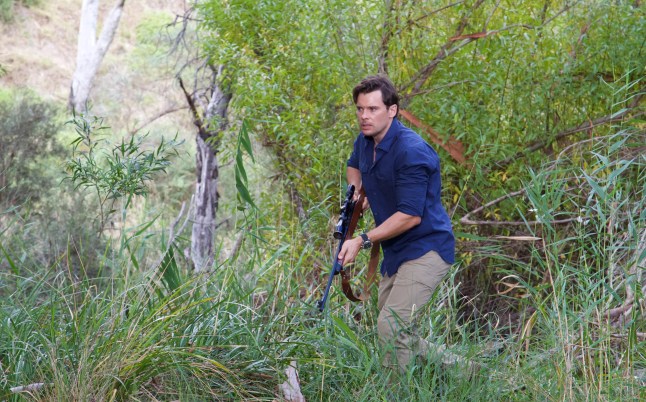 Heath holds a rifle in Neighbours