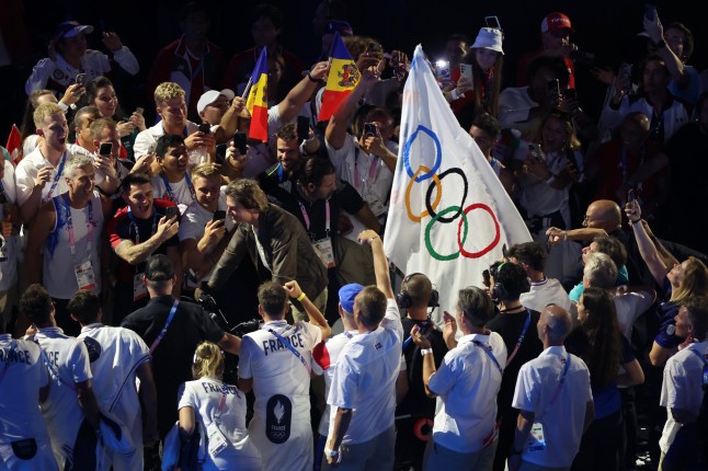 PARIS, FRANCE - AUGUST 11: American Actor and Film Producer Tom Cruise rides on a Motorbike with the IOC Flag during the Closing Ceremony of the Olympic Games Paris 2024 at Stade de France on August 11, 2024 in Paris, France. (Photo by Steph Chambers/Getty Images)