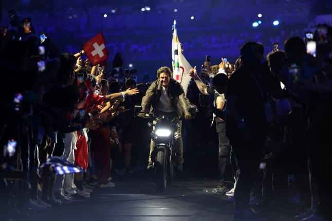 PARIS, FRANCE - AUGUST 11: American Actor and Film Producer Tom Cruise rides on a Motorbike with the IOC Flag during the Closing Ceremony of the Olympic Games Paris 2024 at Stade de France on August 11, 2024 in Paris, France. (Photo by Jamie Squire/Getty Images)