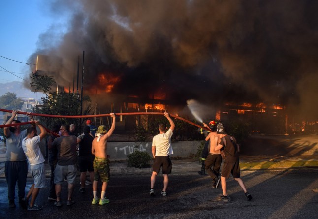 Mandatory Credit: Photo by Dimitris Aspiotis/Shutterstock (14634186p) Volunteers line up holding the water hose while putting out the fire in a shop in the Vrilissia suburb of the Greek capital. A wildfire that broke out in Varnavas on 11 August continued to rage in eastern Attica on 12 August, fanned and spread to a front extending more than 20 kilometers. Several countries have responded positive to the request of Greek authorities for assistance from the EU Civil Protection Mechanism (EUCPM) to combat the wildfire raging. Wildfire reaches suburbs burning houses, Athens, Greece - 12 Aug 2024