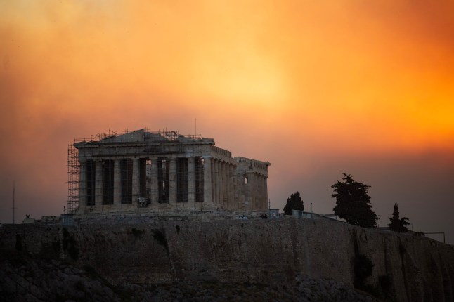 TOPSHOT - This photograph shows the Parthenon temple atop the Acropolis hill in a smoke cloud from a wildfire, in Athens on August 12, 2024. On August 12, 2024, Greece's civil protection authorities ordered the evacuation of several towns in the north-eastern suburbs of Athens, threatened by a violent fire that started the day before and is spreading. (Photo by Angelos TZORTZINIS / AFP) (Photo by ANGELOS TZORTZINIS/AFP via Getty Images)