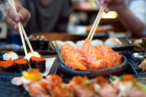 Asian lady eat a Salmon fish sashimi and Sushi in Japanese restaurant