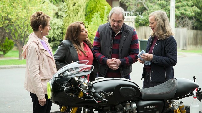 Susan, Terese, Jane and Karl stand around Mike's motorbike in Neighbours