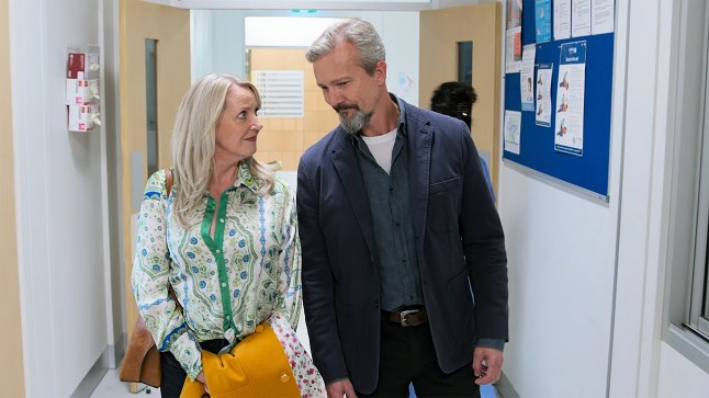 Melanie walks through Erinsborough Hospital with Vic in Neighbours