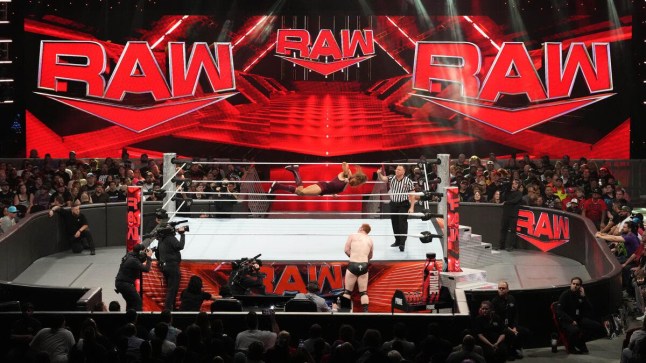 WWE Raw ring and stage, with huge red logos saying 'Raw' in the background