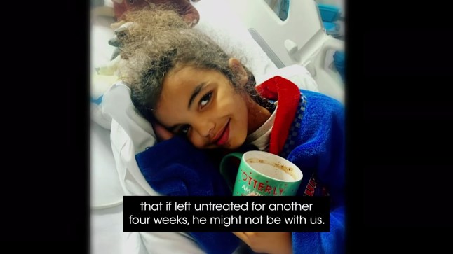 Kaiden lies in hospital bed with sick cup in hand