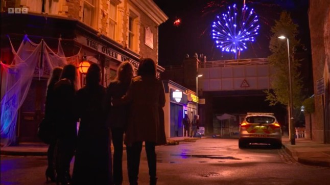 A police car drives Nish out of Walford, with The Six watching on in EastEnders