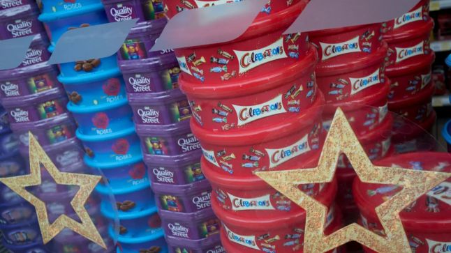 A display of assorted chocolate and sweet boxes of Nestle Quality Street, Cadburys Roses and Heroes plus Mars Celebrations piled up in the Christmas themed window of a local Tescos supermarket, on 20th November 2019, at Smithfield in the City of London, England.