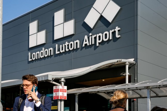 Travelers walk in front of London Luton Airport, London