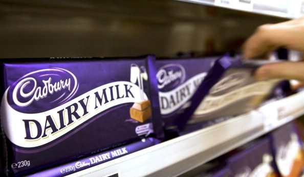 A customer selects a bar of Cadbury's Dairy Milk chocolate in supermarket