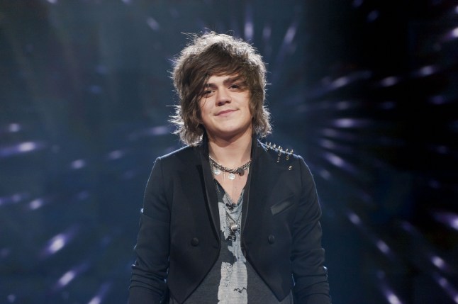 Frankie Cocozza on The X Factor. He is wearing dark clothing and stood smiling on stage