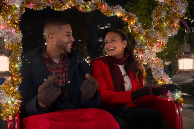 Devale Ellis as Teddy and Christina Milian as Layla laughing in a sleigh together in Meet Me Next Christmas