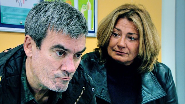 Cain Dingle (Jeff Hordley) purses his lips and looks angry as Moira Dingle looks at him in Emmerdale