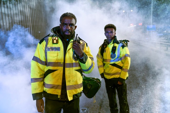 Jacob and Teddy stand in the middle of a crash scene in Casualty