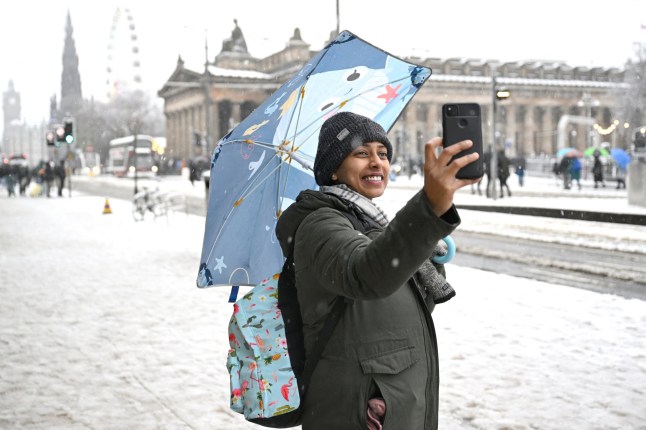 A shopper takes a selfie in the snow during Storm Bert, along Princes Street in Edinburgh, Scotland, Britain, November 23, 2024. REUTERS/Lesley Martin