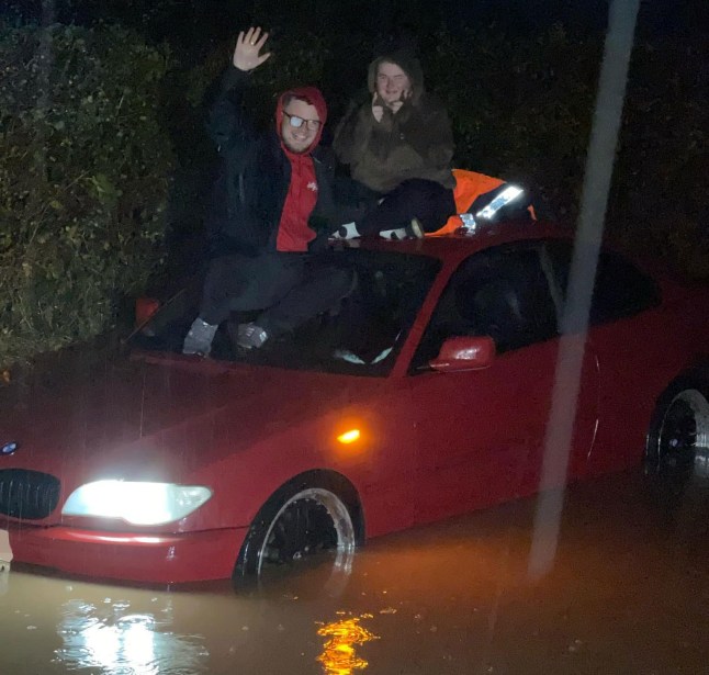 Couple on roof of flooded car.