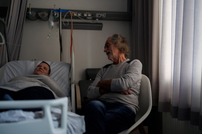 Carer and former doctor Denis Rousseaux talks with Lydie Imhoff (L) in a hospital room in Belgium, on February 1, 2024, as Imhoff waits for the doctor to arrive on the day of her euthanasia. Lydie Imhoff, a 43 year-old French citizen suffering from hemiplegia and blindness from birth due to a perinatal stroke, has been authorized to travel from Besancon, France, to Belgium to undergo euthanasia on February 1, 2024. (Photo by Simon Wohlfahrt / AFP) / SOLELY TO ILLUSTRATE THE EVENT AS SPECIFIED IN THE CAPTION ANY USE IN ANOTHER CONTEXT WILL ENTAIL LIABILITY ON YOUR PART (Photo by SIMON WOHLFAHRT/AFP via Getty Images)