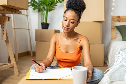 African american woman sitting in her room checking her to-do list.