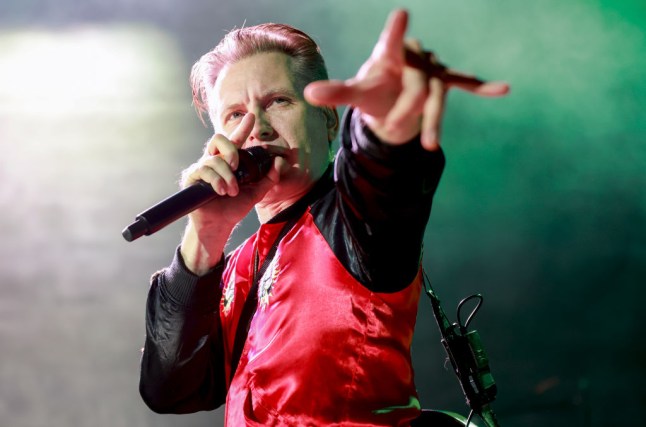 Alex Kapranos of Franz Ferdinand singing into a microphone while pointing into the crowd