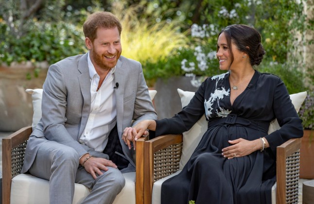 Meghan Markle and Prince Harry sat in chairs in formal clothing in an interview with Oprah Winfrey