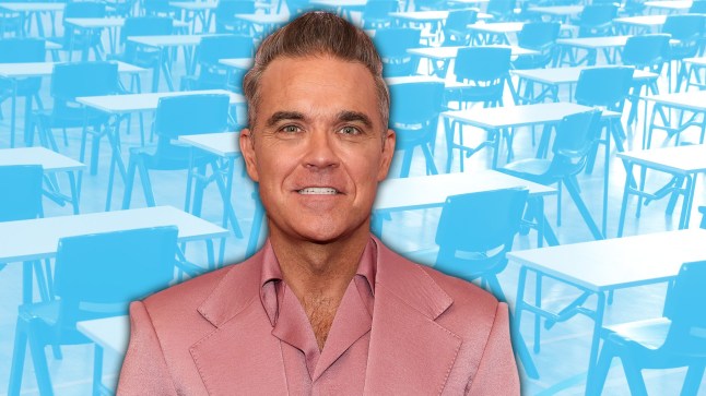 Robbie Williams smiles as he poses in a salmon-coloured suit and matching silk shirt with a blue background of an exam room with chairs and tables behind him