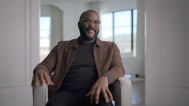 Tyler Perry sat in a chair wearing a brown jacket and black top during Harry & Meghan Netflix series