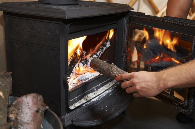 Man Putting Log Onto Wood Burning Stove; Shutterstock ID 347112407; purchase_order: -; job: -; client: -; other: -