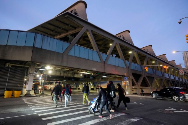 Pedestrians cross the road outside George Washington Bridge Bus Station in New York, Friday, Dec. 6, 2024, where the gunman fleeing Wednesday's shooting of UnitedHealthcare CEO Brian Thompson took a taxi to, according to surveillance video. (AP Photo/Richard Drew)