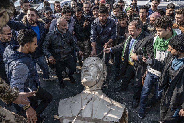 DAMASCUS, SYRIA - DECEMBER 9: Citizens in Syria take down statues of Hafez al-Assad the father of Bashar al-Assad, in Damascus, Syria on December 9, 2024. With Sunday's collapse of Syria's Baath regime and the end of the Assad family era, Syrians were seen toppling statues of Hafez al-Assad, the father of ousted President Bashar al-Assad, in various cities across the country. (Photo by Murat Sengul/Anadolu via Getty Images)