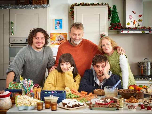 Hugh Dennis as Pete Brockman, Claire Skinner as Sue Brockman, Tyger Drew-Honey as Jake Brockman, Daniel Roche as Ben Brockman and Ramona Marquez as Karen Brockman in OUtnumbered. They are all stood around a kitchen island filled with food.