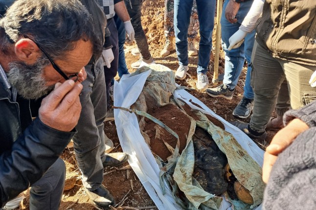 Sanitary workers check human remains from a newly uncovered mass grave discovered in an agricultural field in Izra, in Syria's southern Daraa province, on December 16, 2024. Islamist-led rebels took Damascus in a lightning offensive on December 8, ousting president Bashar al-Assad and ending five decades of Baath rule in Syria. According to the Syrian Observatory for Human Rights, more than 100,000 people died in Syria's jails and detention centres from 2011. (Photo by Sam HARIRI / AFP) (Photo by SAM HARIRI/AFP via Getty Images)