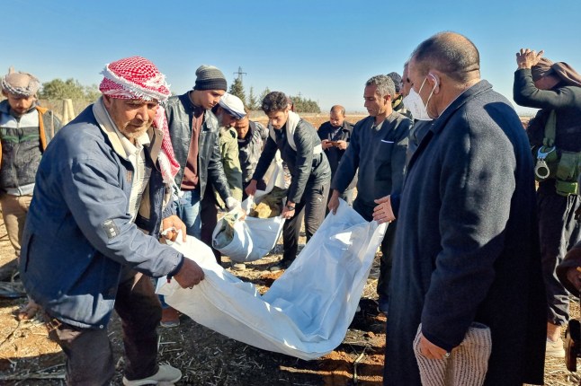 Sanitary workers carry human remains from a newly uncovered mass grave discovered in an agricultural field in Izra, in Syria's southern Daraa province, on December 16, 2024. Islamist-led rebels took Damascus in a lightning offensive on December 8, ousting president Bashar al-Assad and ending five decades of Baath rule in Syria. According to the Syrian Observatory for Human Rights, more than 100,000 people died in Syria's jails and detention centres from 2011. (Photo by Sam HARIRI / AFP) (Photo by SAM HARIRI/AFP via Getty Images)