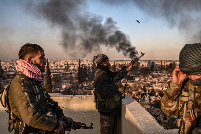 TOPSHOT - Gunmen stand on the roof of a building to push away looters from the Najha military housing complex in southeast Damascus on December 17, 2024. Islamist-led rebels took Damascus in a lightning offensive on December 8, ousting president Bashar al-Assad and ending five decades of Baath rule in Syria. (Photo by Aris MESSINIS / AFP) (Photo by ARIS MESSINIS/AFP via Getty Images) *** BESTPIX ***