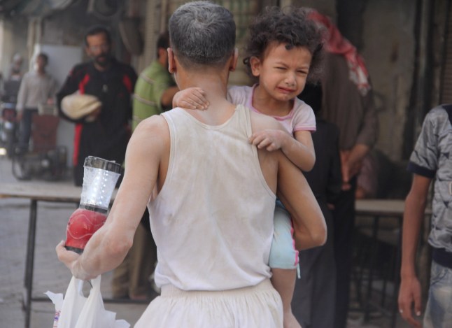 ALEPPO, SYRIA - AUGUST 22 : A man carrying a crying child and some belongings is taking them to a safe zone following Assad forces barrel bomb attack to Qadi Askar neighborhood leaving casualties on August 22, 2015, Aleppo, Syria. (Photo by Ahmed Muhammed Ali/Anadolu Agency/Getty Images)