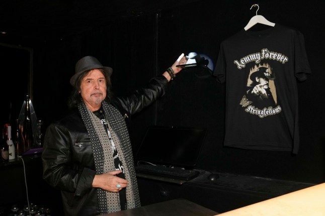 Phil Campbell posing next to the urn that contains part of the ashes of Lemmy from Motorhead, behind the bar at Stringfellows nightclub in London