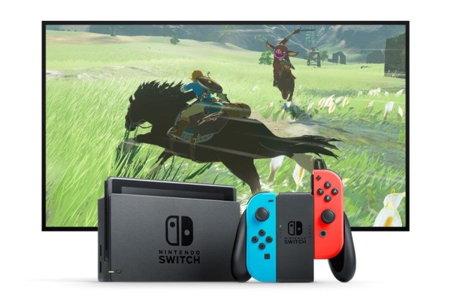 Nintendo Switch in its dock next to Joy-Con controllers in gamepad with a TV displaying Link riding a horse through a field in the background