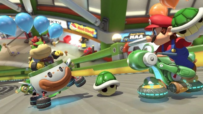 Mario Kart 8 Deluxe Mario riding bike holding green shell approaching Bowser Jr in a go kart