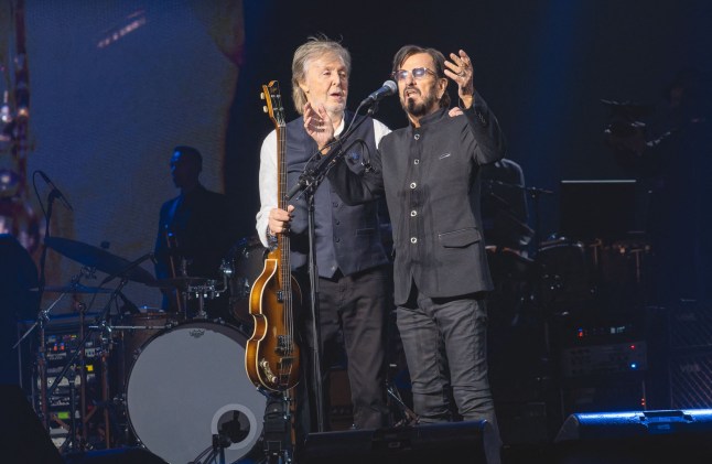 Sir Paul McCartney and Sir Ringo Starr embracing each other on stage as Paul holds a ukuele