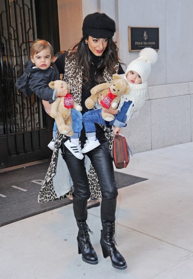 Amal Clooney walking through hte street carrying her two children