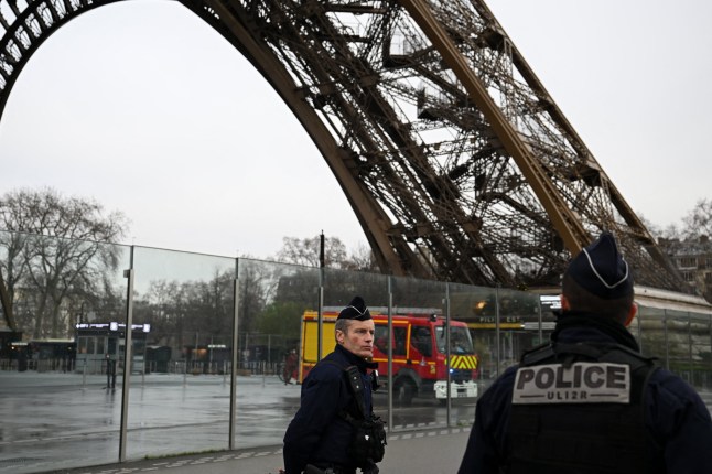 French police and firefighters stand at the bottom of the Eiffel Tower, where a fire was reported in Paris, on December 24, 2024. (Photo by Anna KURTH / AFP) (Photo by ANNA KURTH/AFP via Getty Images)