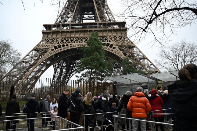 Visitors queue at the bottom of the Eiffel Tower as the site was closed and then reopened after a fire was reported in Paris, on December 24, 2024. (Photo by Anna KURTH / AFP) (Photo by ANNA KURTH/AFP via Getty Images)