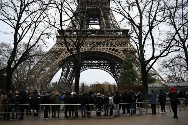 Visitors queue at the bottom of the Eiffel Tower as the site was closed and then reopened after a fire was reported in Paris, on December 24, 2024. (Photo by Anna KURTH / AFP) (Photo by ANNA KURTH/AFP via Getty Images)