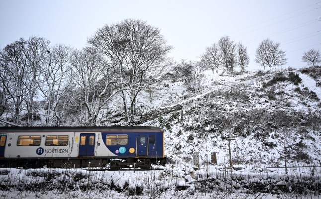 A Northern Rail train travels on tracks past snow in Buxton, northern England, on November 19, 2024. (Photo by Paul ELLIS / AFP) (Photo by PAUL ELLIS/AFP via Getty Images)