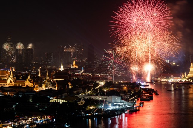 BANGKOK, THAILAND - JANUARY 01: Fireworks light up the night sky as the Tourism Authority of Thailand (TAT) marks the transition to 2025 with a fireworks display themed 'SIAMSMILE,' featuring nine acts symbolizing aspects of Thai tourism: Sustainable Tourism, Imagination, A Paradise to Explore, Mutual Respect, Smiling People, Memories, Inner Peace, Love, and Endless Happiness. The display was visible along the Chao Phraya River and from Sanam Luang in Bangkok, Thailand, on January 01, 2025. (Photo by Matt Hunt/Anadolu via Getty Images)