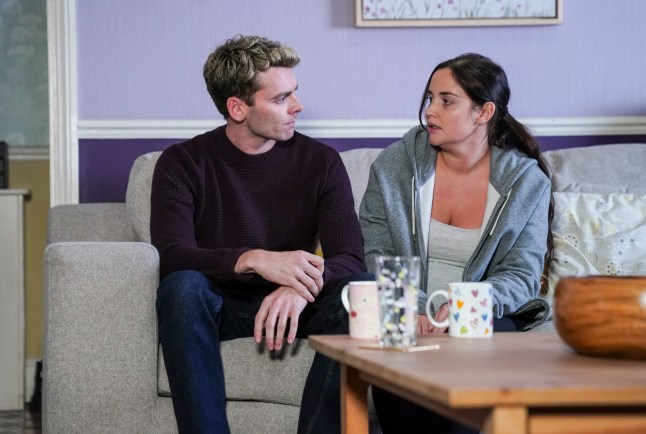 Peter and Lauren look at eachother sat on the sofa in EastEnders