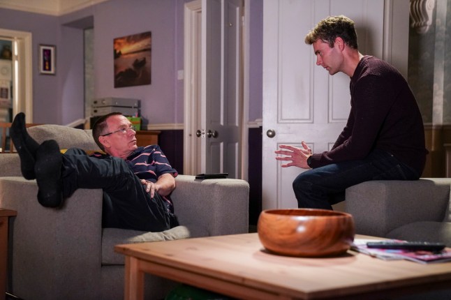 Peter talks to Ian, who is slumped over an armchair in EastEnders