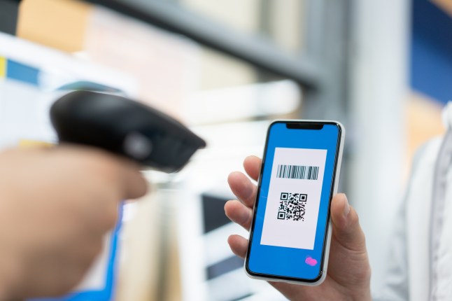 Man is using mobile phone QR code to checkout